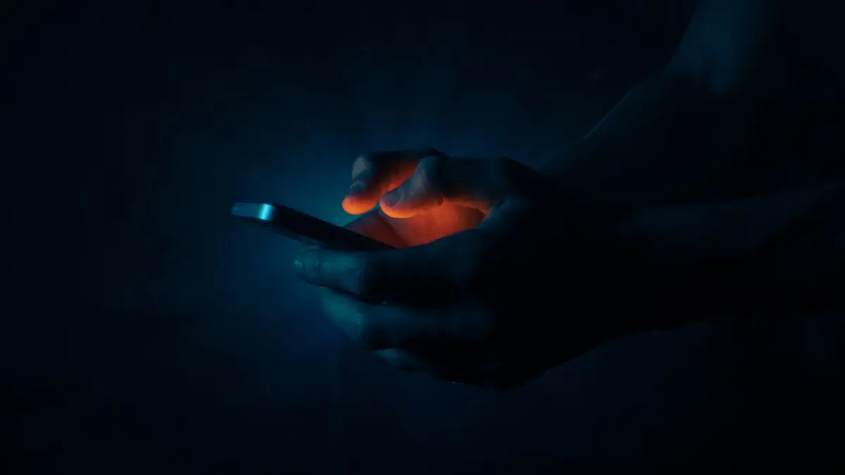 A phone glowing in a dark room, the only light at night